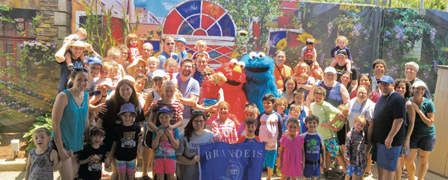 Large group of adults and kids surround people dressed in Elmo and Cookie Monster costumes